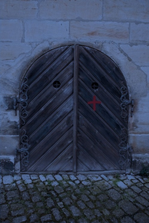 puerta de madera con una cruz roja noche en la calle del codo