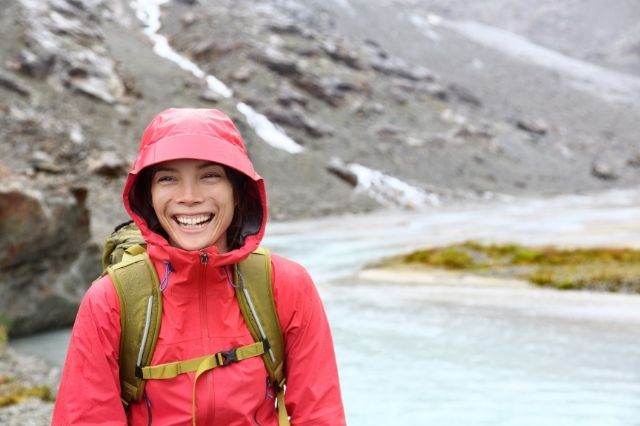 mochilera sonriendo bajo la lluvia