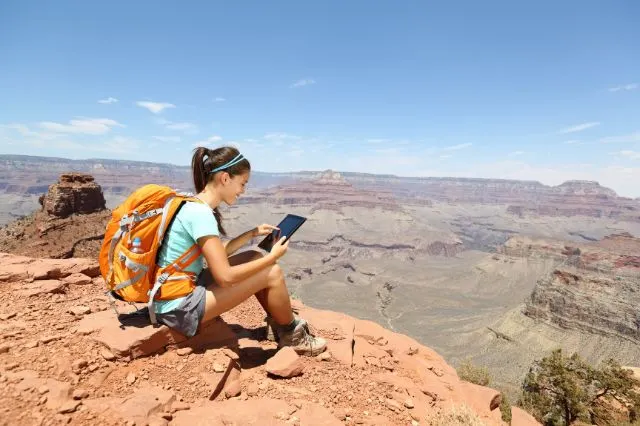 viajera usando una tablet en la cima de una montaña